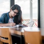 photo from unsplash / girl sitting at a table doing homework / WLOY