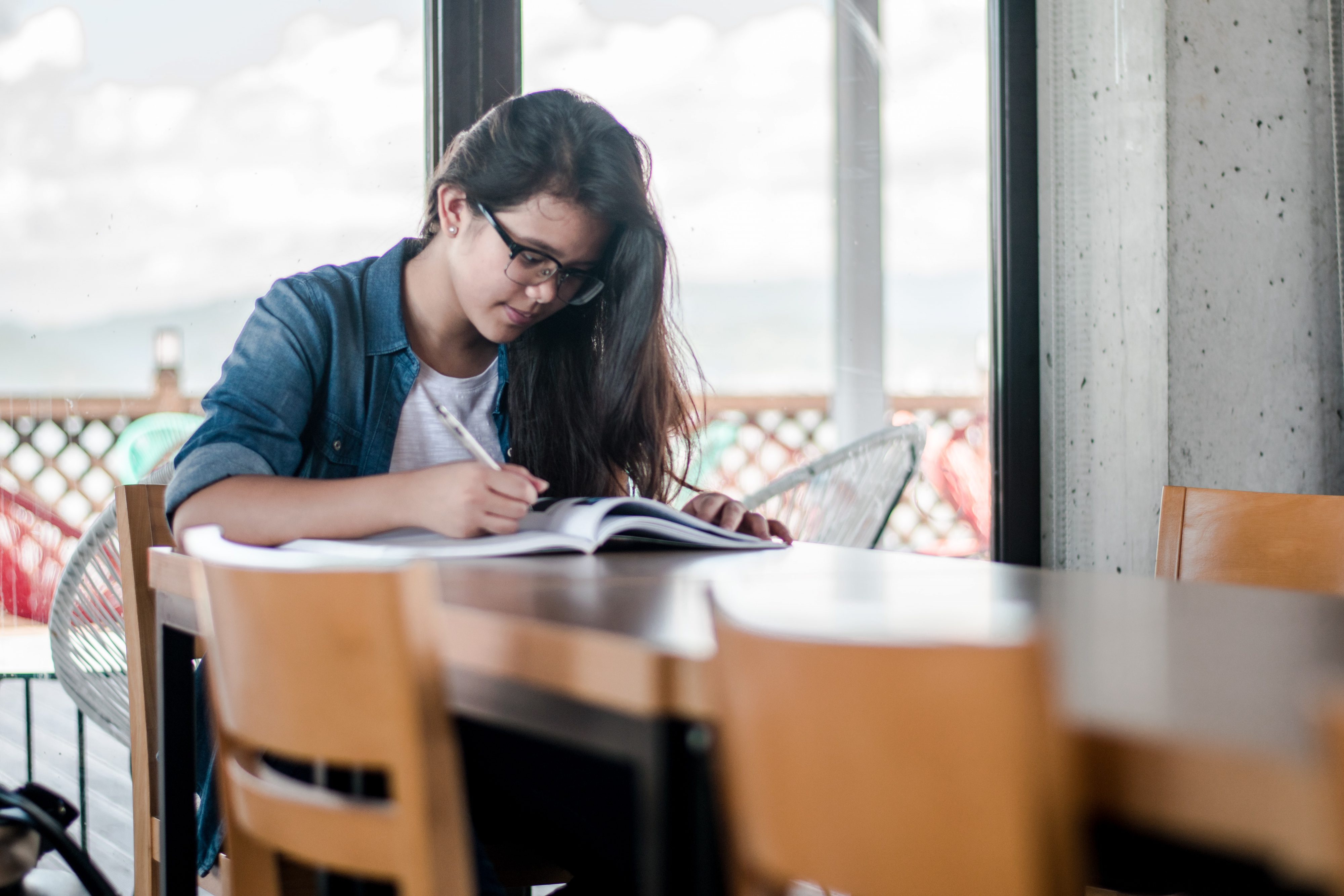 photo from unsplash / girl sitting at a table doing homework / WLOY