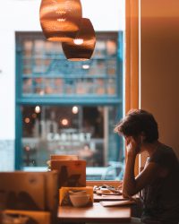 photo by Reinhart Julian on Unsplash / girl sitting at a table by the window studying / WLOY